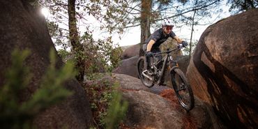 Ein Mann fährt auf einem Scott Fully MTB einen steinigen Trail hinunter